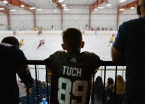 A boy in the stands wears an Alex Tuch jersey watching the Alex Tuch 3 on 3 Pro Hockey Game to benefit Maureen's Hope Foundation.