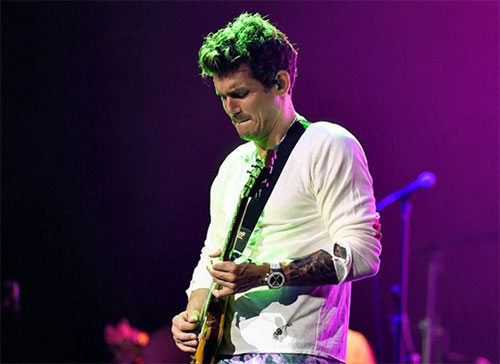 Singer John Mayer, bathed in green and purple stage lights, plays guitar during his concert while wearing a Bead of Courage for Maureen?s Hope Foundation.